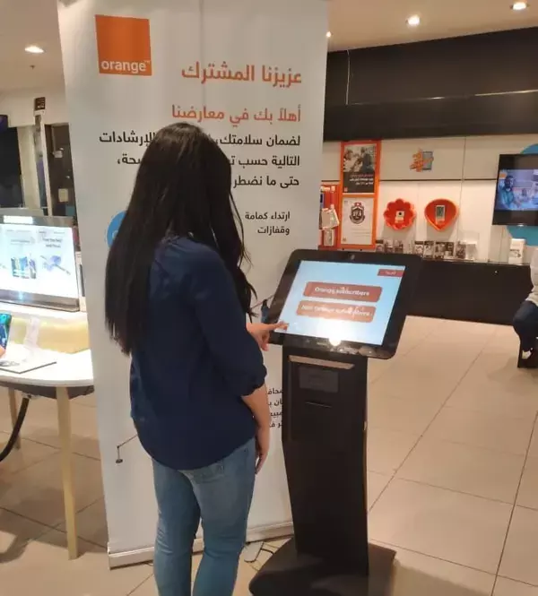 woman using SEDCO's queuing kiosk at Orange Jordan woman using SEDCO's queuing kiosk at Orange Jordan